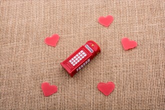 Red hearts around red color phone booth on canvas