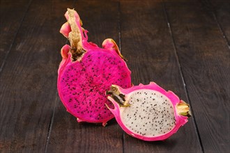 Two dragon fruits sliced on half on wooden table