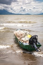 A fishing boat on the shore of a lake with volcanoes in the background. A fishing boat on a lake in Nicaragua. Concept of fishing boats parked at the seaside