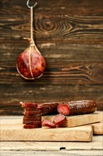 Smoked dried deer sausage cut on slices on wooden cutting board