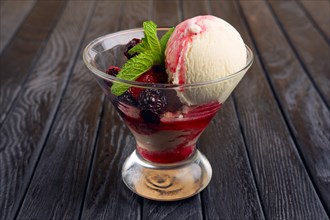 A cup of raspberries ice cream decorated with dewberry and mint leaves