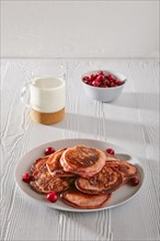 Pancakes with cherry and glass of milk on white kitchen table