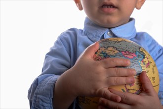 Baby with blue shirt holding a globe in hand on white background