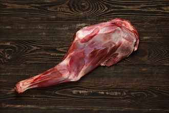 Overhead view of raw doe leg over wooden background