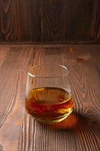 Snifter glass with pure whiskey on wooden table