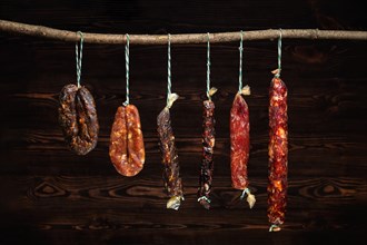 Variety of dried sausage on twine hanging in country wooden barn
