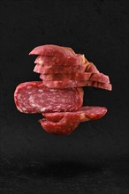 Levitating slices of smoked beef sausage over black background
