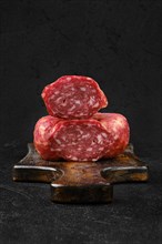 Closeup view of smoked beef sausage on cutting board over black background