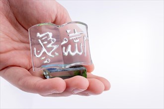 Hand holding Miniature Holy Quran on a white background