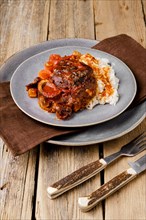Overhead view of plate with ossobuco on wooden table