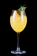 Cold orange lemonade with rosemary scent in a wine glass isolated on black background