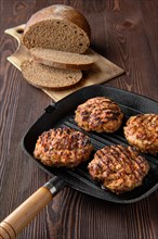 Cast iron grill skillet with beef cutlets and freshly baked brown bread
