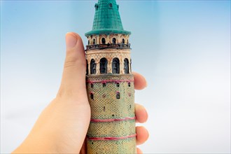 Hand holding a model of the Galata Tower in Istanbul
