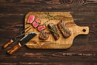 Top view of grilled beef steak on shabby cutting board