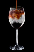Pouring spresso in cocktail with tonic in wine glass isolated on black background