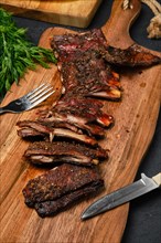 Top view of grilled lamb breast ribs on wooden cutting board