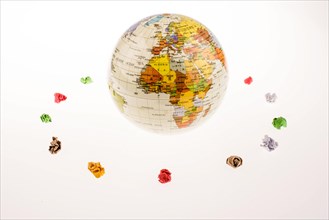 Colorful crumpled papers form a round shape around a globe on white background