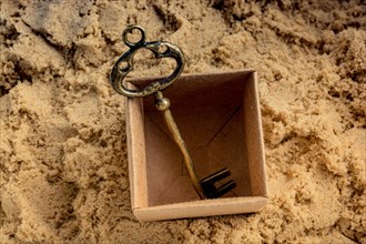 Retro style key placed in a brown box on sand