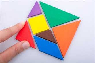 Hand holding a missing piece in a tangram puzzle