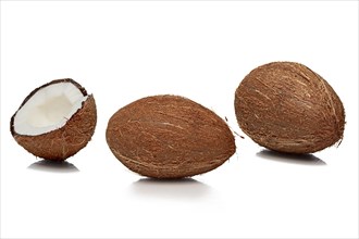 Two whole and one cut half coconuts with shadow on white background