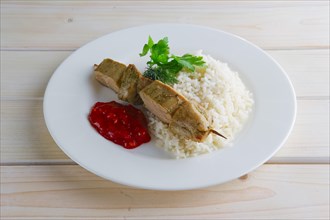 Plate with pork shaslyk with rice and tomato sauce on wooden table