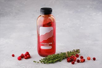 Small bottle with cranberry and thyme lemonade on the table