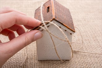 Thread wrapped around a model house on a brown background