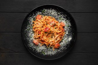 Top view of spaghetti with tomato cherry and grated parmesan on a plate