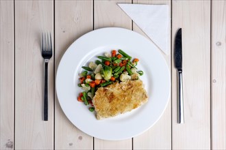 Top view of plate with fried fish and vegetables