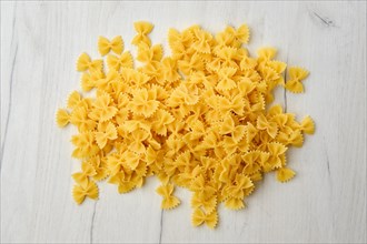 Top view of raw farfalle pasta with spice and herbs on wooden background