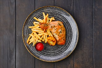 Top view of baked chicken thigh with french fries