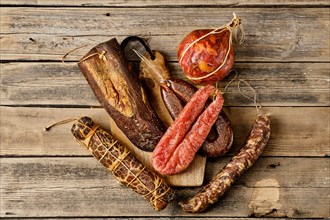 Top view of assortment of dried meat and sausages on wooden background