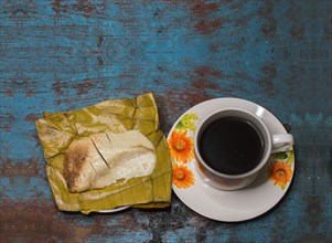 Traditional Stuffed Pisque Tamal with cup of coffee served on wooden table
