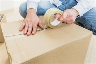 Young man sealing cardboard box with tape big moving. Resolution and high quality beautiful photo
