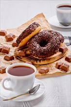Chocolate donuts and coffee on white wooden background