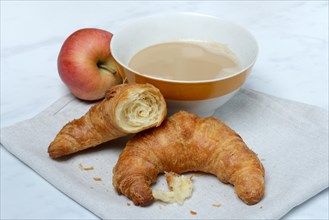 Coffee with milk in bowl and croissant