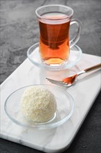 Closeup view of coconut biscuit dough cake and a cup of tea on a table