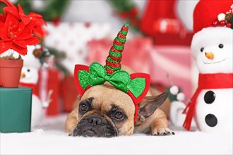 Christmas dog. French Bulldog wearing unicorn headband in front of seasonal decoration
