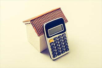 Model house and calculator placed on white background