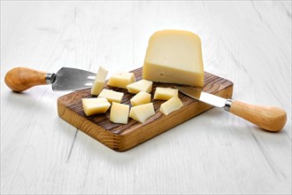 Goat cheese cut on pieces on wooden cutting board