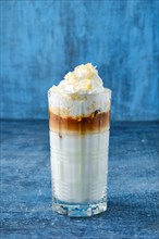 Tall glass of milkshake with whipped cream and peanut flakes