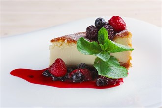 Cheesecake with berries sauce and green mint leaf