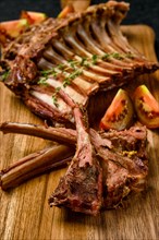 Closeup view of grilled rack of lamb on a plate with spicy sauce
