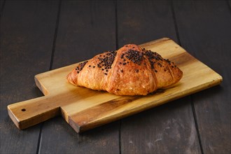Croissant with chockolate icing on wooden serving board