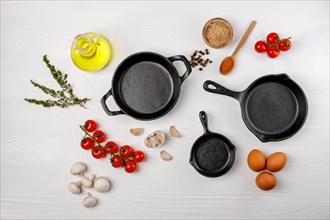 Cast iron skillets and spices on white wooden culinary background