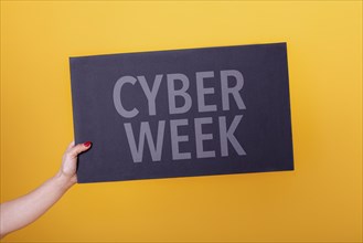 Female hand holding a cyber week poster. Studio shot