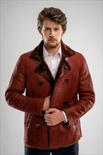 Brutal handsome unshaven man with beard and moustache in sheepskin coat with fur collar