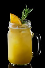 Mug with orange and lemon cocktail isolated on black background