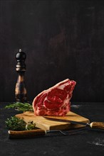 Raw strip steak bone in on dark background