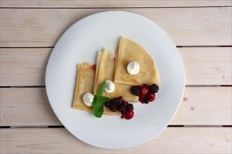 Portion on thin pancakes with sweet cream cheese and berries. Top view